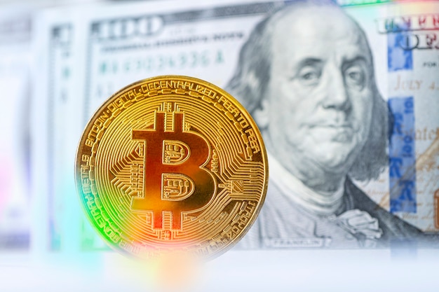 Business concept of worldwide cryptocurrency. Golden bitcoin with Benjamin Franklin portrait from one hundred american dollars.