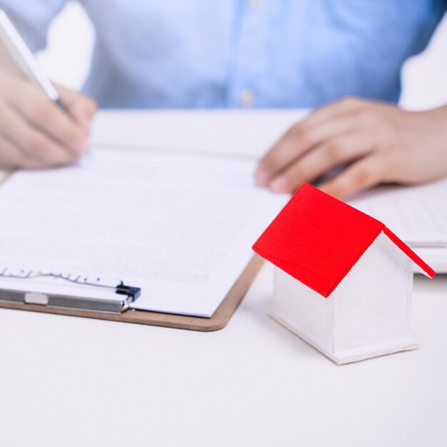 Photo business concept young asian man in blue shirt calculates signs agreement contract to buy a house loan payment paying insurance tax close up