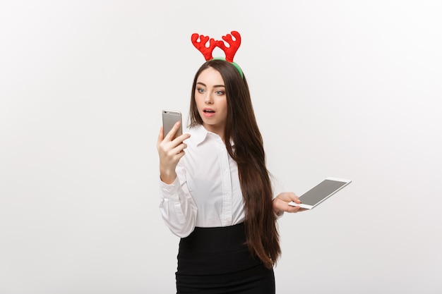 Бизнес-концепция - молодая кавказская бизнес-леди в рождественской теме играет по мобильному телефону с удивительным выражением лица.