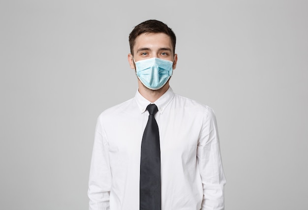 Business Concept - Young successful businessman in face mask posing over dark wall. Copy space.