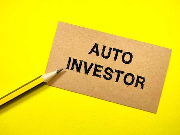 Business concepttext auto investor on brown card with pencil on
yellow background