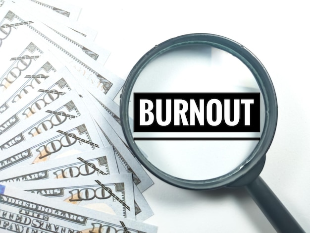 Business conceptText BURNOUT met vergrootglas en bankbiljet op witte achtergrond