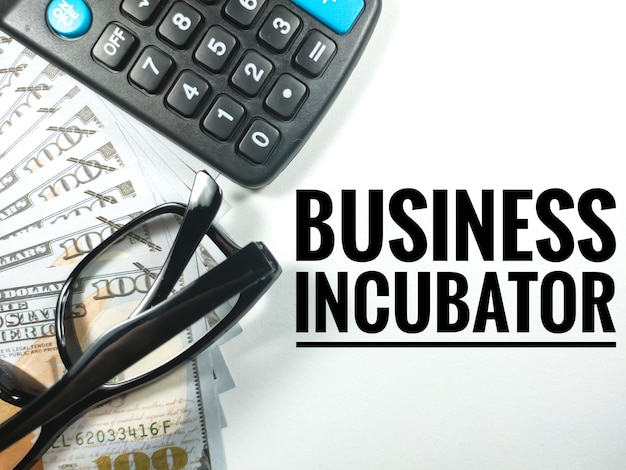 비즈니스 conceptText BUSINESS INCUBATOR with calculatorglasses 및 지폐 흰색 배경에