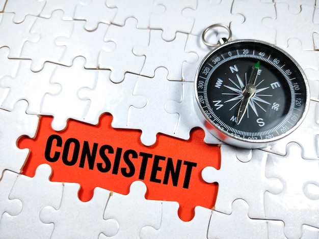 Business conceptText CONSISTENT met puzzel en kompas op rode achtergrond