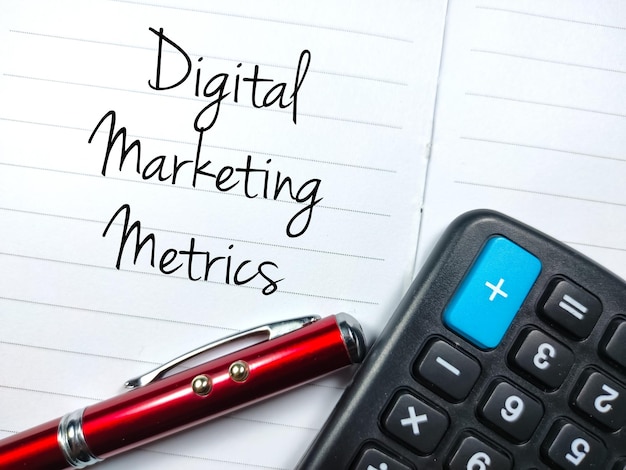 Business conceptText Digital Marketing Metrics schrijven op notebook met pen en rekenmachine