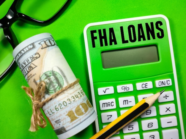 ビジネス コンセプトテキスト FHA ローンは、緑の背景に鉛筆ドルのお金とメガネで電卓に書く