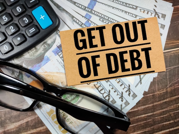 Foto concetto di businesstesto esci dal debito con occhiali da calcolatrice e banconota su sfondo di legno marrone