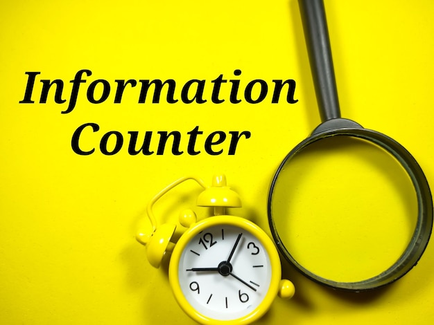 Business concepttext information counter with magnifying glass\
and alarm clock on yellow background