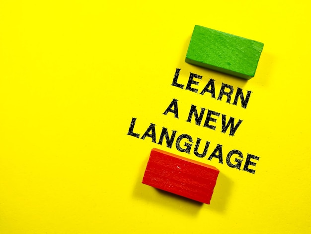 Business conceptText LEARN A NEW LANGUAGE with colored block on a yellow background