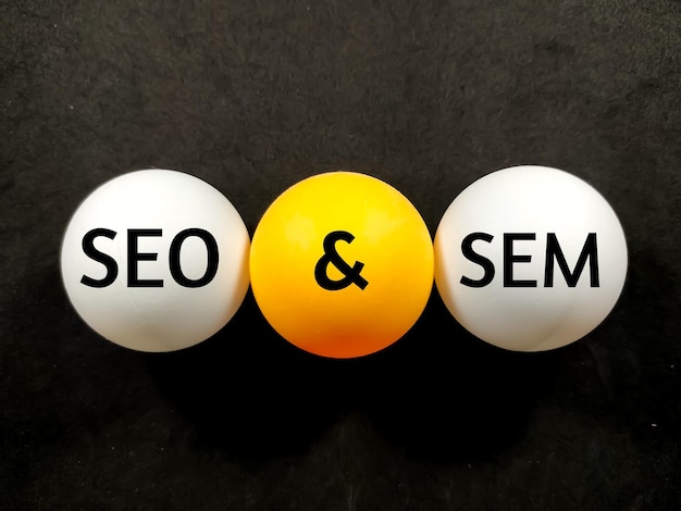 Business conceptText SEO AND SEM writing on ping pong ball on a black background