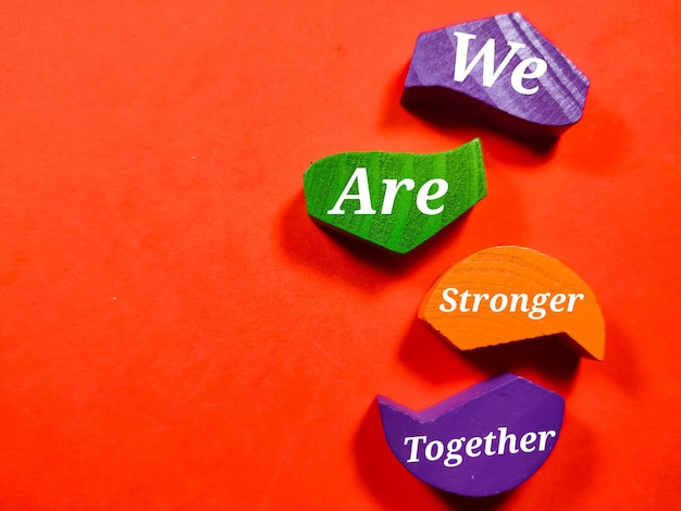 Photo business concepttext we are stronger together with colored wooden block isolated on a red background