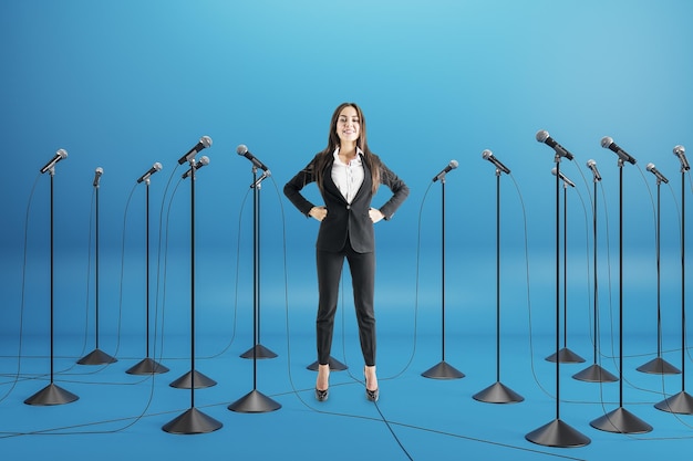 Business conference concept with businesswoman speaker among floor stand microphones