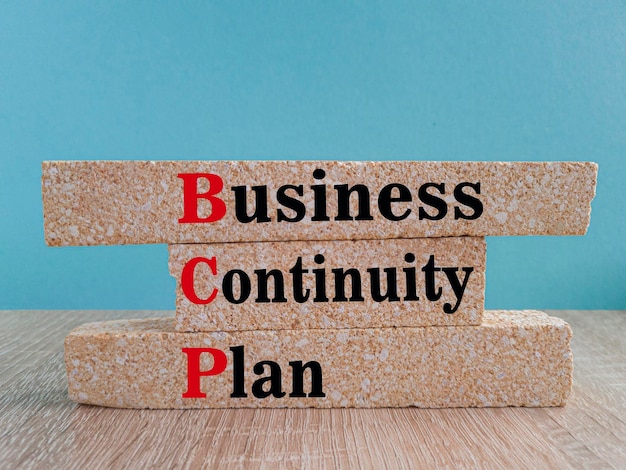 Символ плана непрерывности бизнеса На ярко-синем фоне кирпичные блоки с текстом BCP
