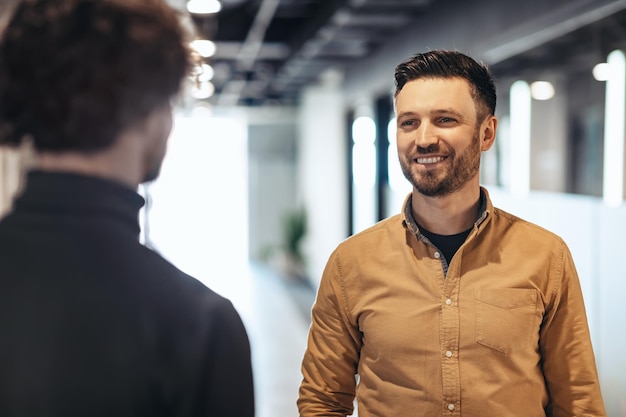 Business cooperation concept happy male colleagues standing face to face smiling at each other