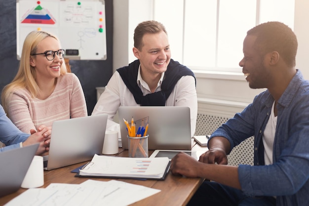 Business corporate meeting of multiethnic team. Young cheerful people brainstorming, discussing new startup project in office, copy space