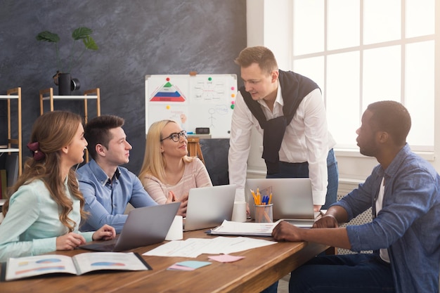 Business corporate meeting of multiethnic team. Young cheerful people brainstorming, discussing new startup project in office, copy space