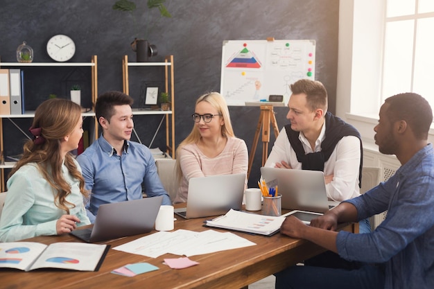 Business corporate meeting of multiethnic team. Young cheerful people brainstorming, discussing new startup project in office, copy space