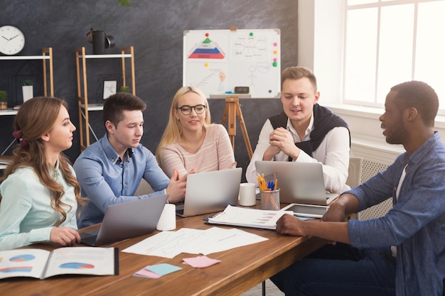 Riunione aziendale aziendale del team multietnico. giovani persone di successo felici che fanno brainstorming, discutono di un nuovo progetto di avvio in ufficio, copiano lo spazio