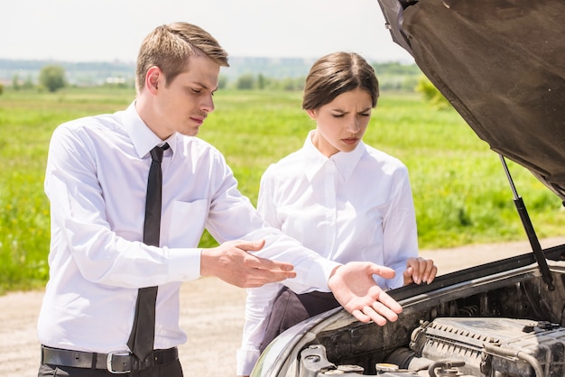 Business couple having argument by broken car.