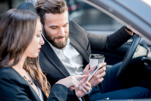 Business couple having a conversation while driving a car in the city