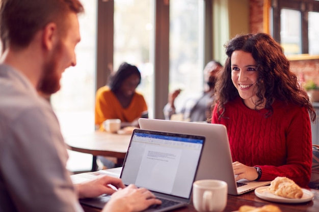 Business Couple With Laptops Having Informal Meeting In Coffee Shop