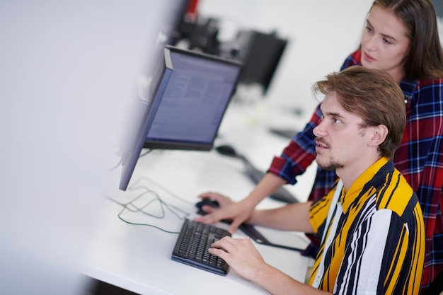 Business couple working together on project using tablet and\
desktop computer at modern open plan startup office