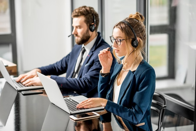 Colleghi d'affari vestiti con abiti che hanno una conferenza online con auricolare e laptop seduti in ufficio