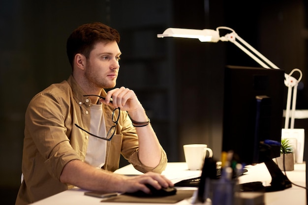 business deadline and technology concept man with computer working at night office