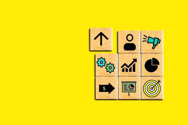 Business development strategy icons on wooden cube isolated on yellow background