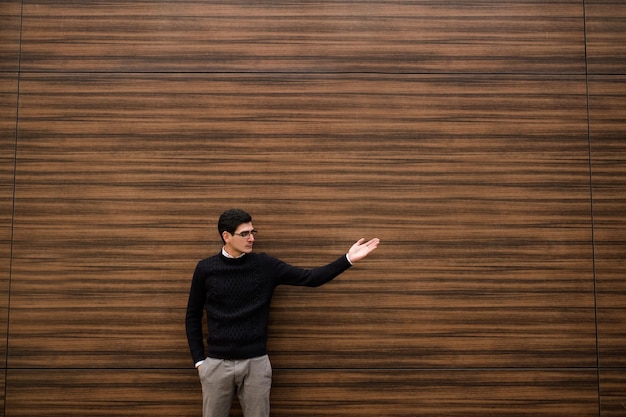 business direction. professional achievement. look there. man attracts attention by pointing hands to virtual text or advertising. wood texture wall background. outdoors street. copyspace concept