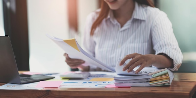 Business Documents concept Employee woman hands working in Stacks paper files for searching and checking unfinished document achieves on folders papers at busy work desk office Soft focus