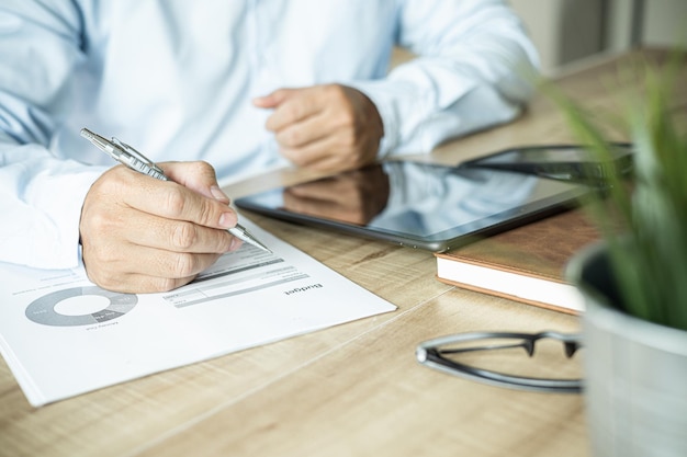 Business documents on office table with digital tablet and\
graph business with social network diagram and man working in the\
office