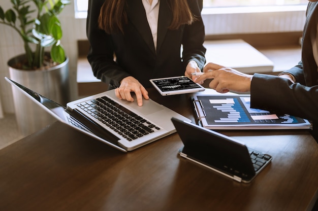 Documenti aziendali sul tavolo dell'ufficio con smartphone e calcolatrice tablet digitale e grafico aziendale con diagramma di social network e due colleghi che discutono i dati che lavorano in ufficio