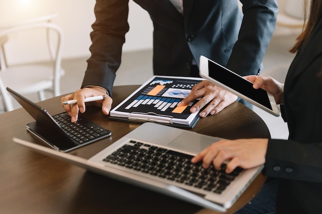 Business documents on office table with smart phone and calculator digital tablet and graph business with social network diagram and two colleagues discussing data working