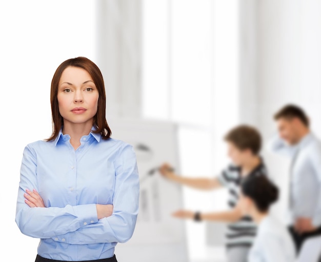 business and education concept - friendly young businesswoman with crossed arms at office