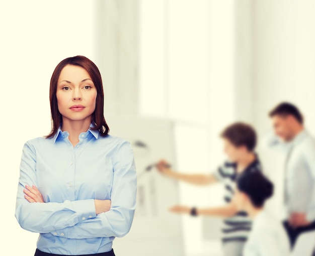 business and education concept - friendly young businesswoman with crossed arms at office