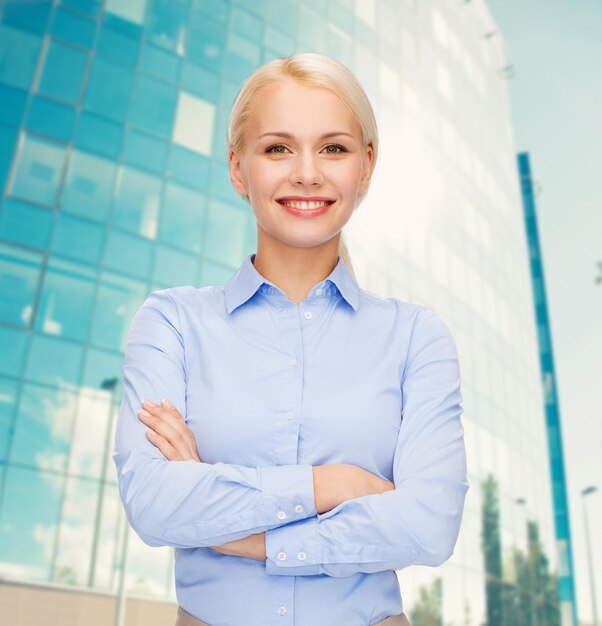 Business and education concept - friendly young smiling businesswoman with crossed arms