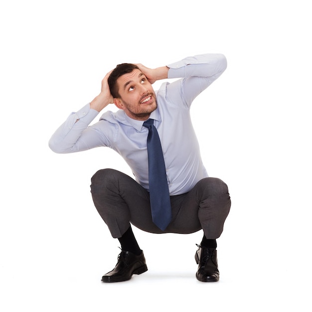 business and education concept - smiling businessman crouching on the floor