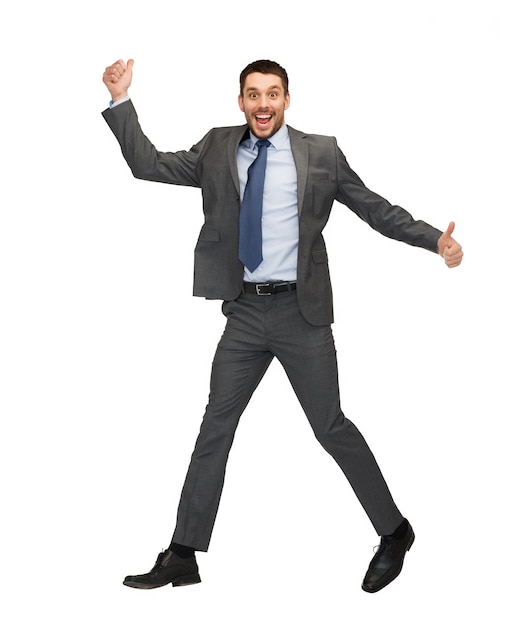 концепция бизнеса и образования - улыбающийся бизнесмен прыгает и показывает палец вверх