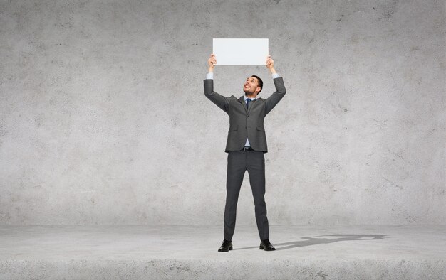 business, education, office and advertising concept - smiling businessman with small white blank board