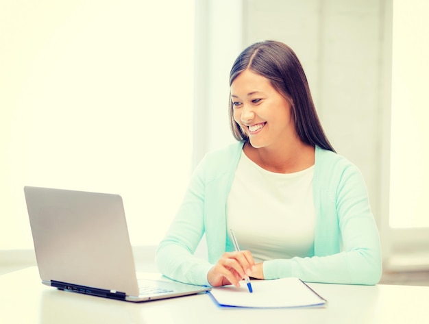 концепция бизнеса, образования и технологий - азиатская деловая женщина или студент с ноутбуком и документами в офисе