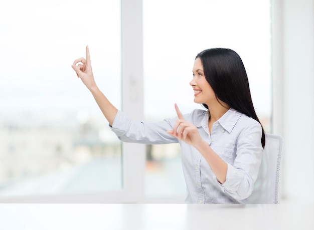 business, education and technology concept - smiling woman pointing to something or pressing imaginary button