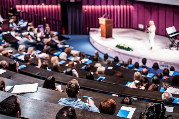 Foto simposio sulle imprese e l'imprenditorialità relatrice che tiene un discorso in una riunione aziendale pubblico nella sala conferenze vista posteriore di un partecipante non riconosciuto nel pubblico