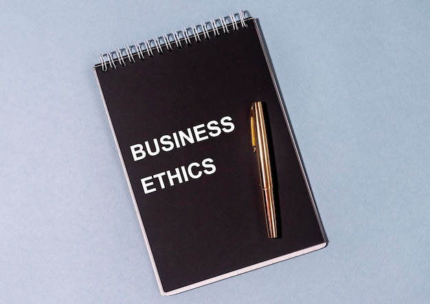 BUSINESS ETHICS inscription on black notepad and golden pen