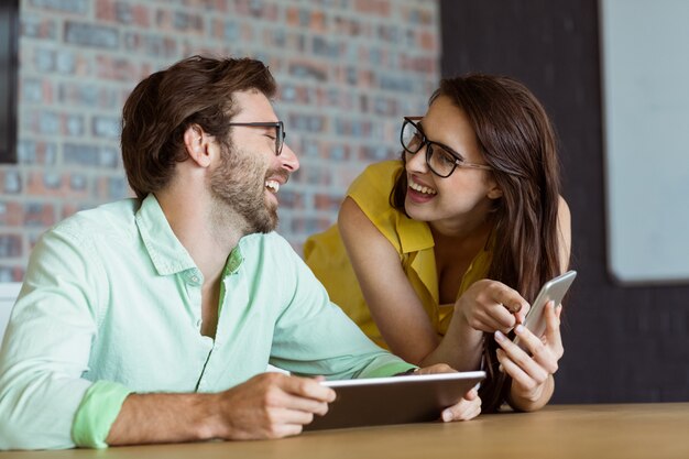 Business executive and co-worker interacting while using digital tablet