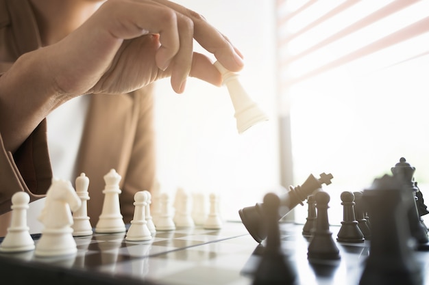 business executive playing chess on board in office, strategy and competition concept