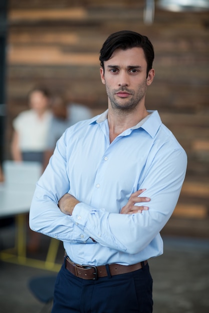 Business executive standing with arms crossed in office