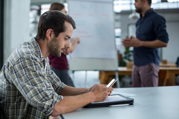 Business executive using mobile phone in a meeting