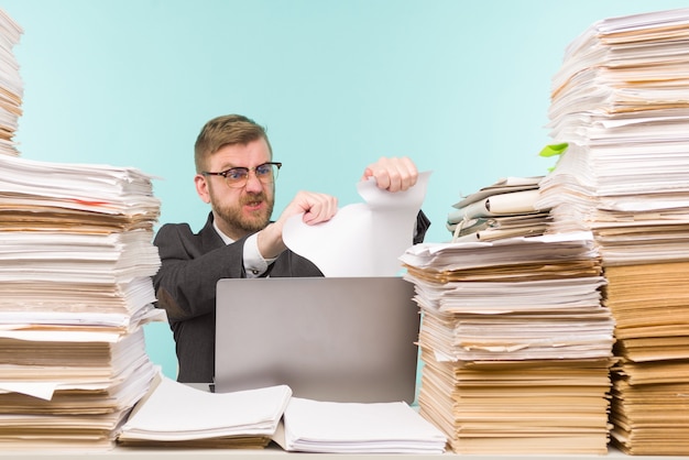 オフィスで働いている経営者と書類の山、彼は仕事でいっぱいです。紙の契約を破り、仕事を辞める-