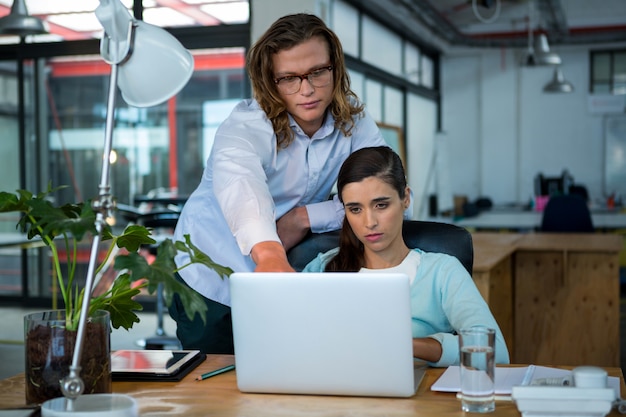 Business executives discussing over laptop